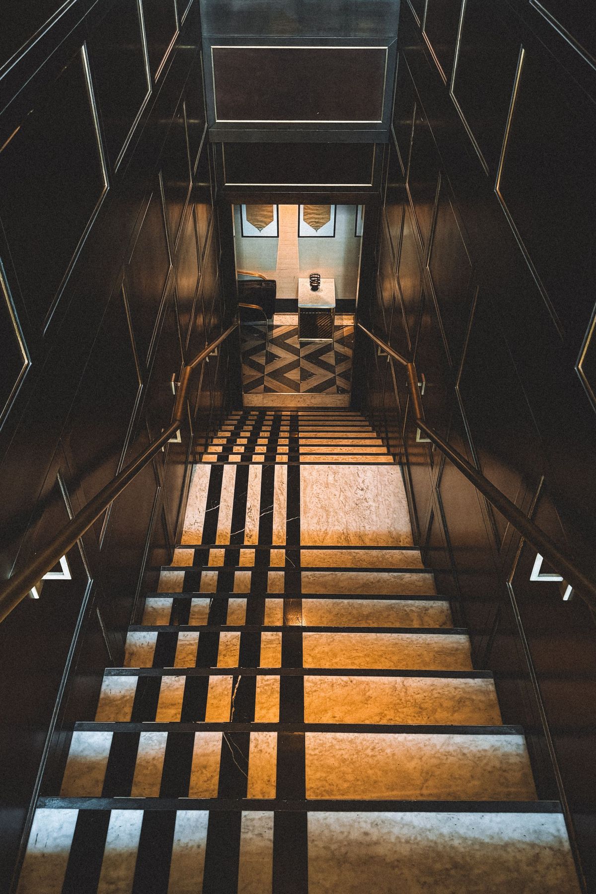 Escalier Art déco aux marches de marbre et rampes de laiton, dans une lumière dorée