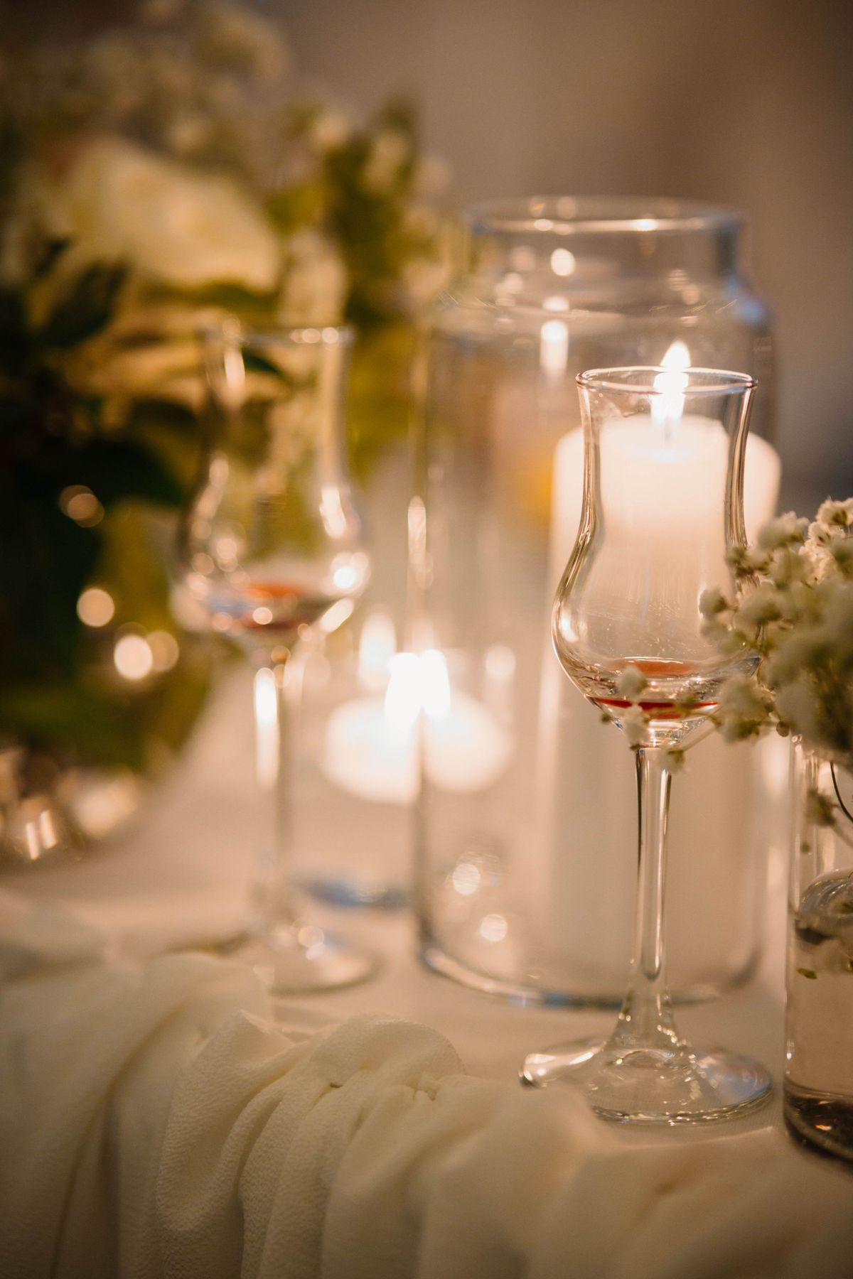 Table de fête aux bougies, verres en cristal et fleurs blanches